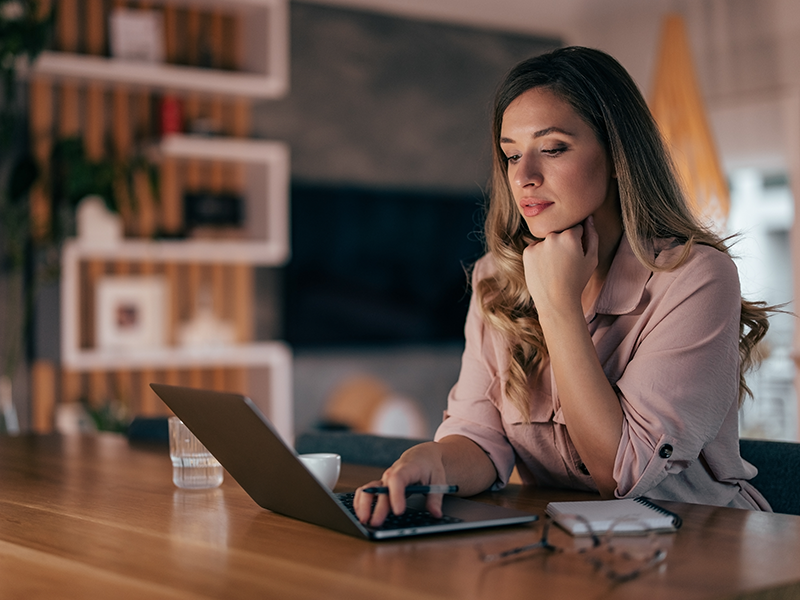 woman on computer with pen in hand