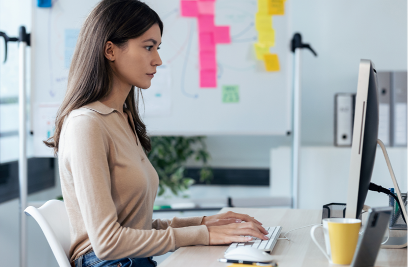 Woman on computer with pen on desk